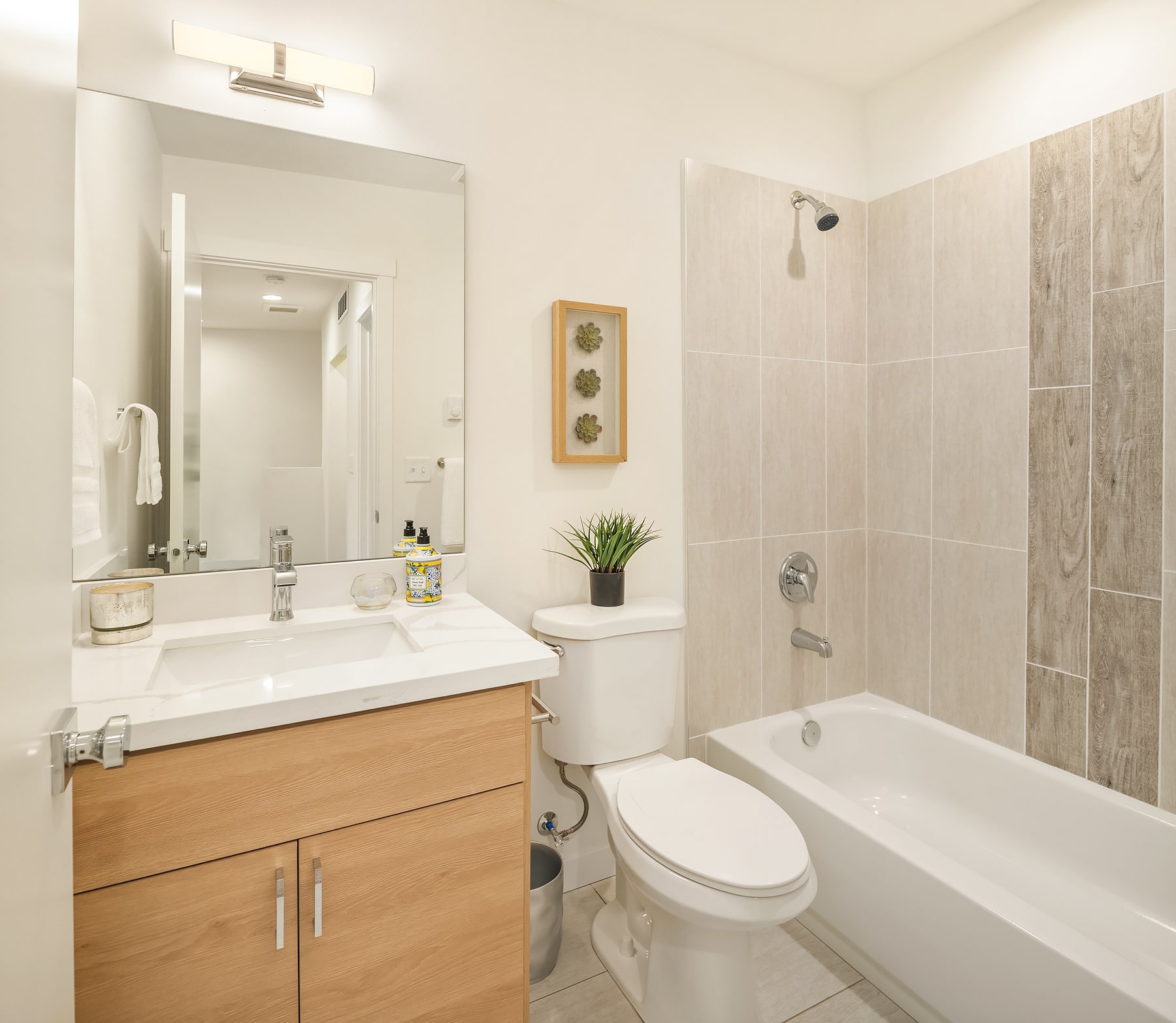 A clean, modern bathroom with light wood cabinetry, white countertops, and a bathtub, showcasing interior design elements used in TP Home builds.