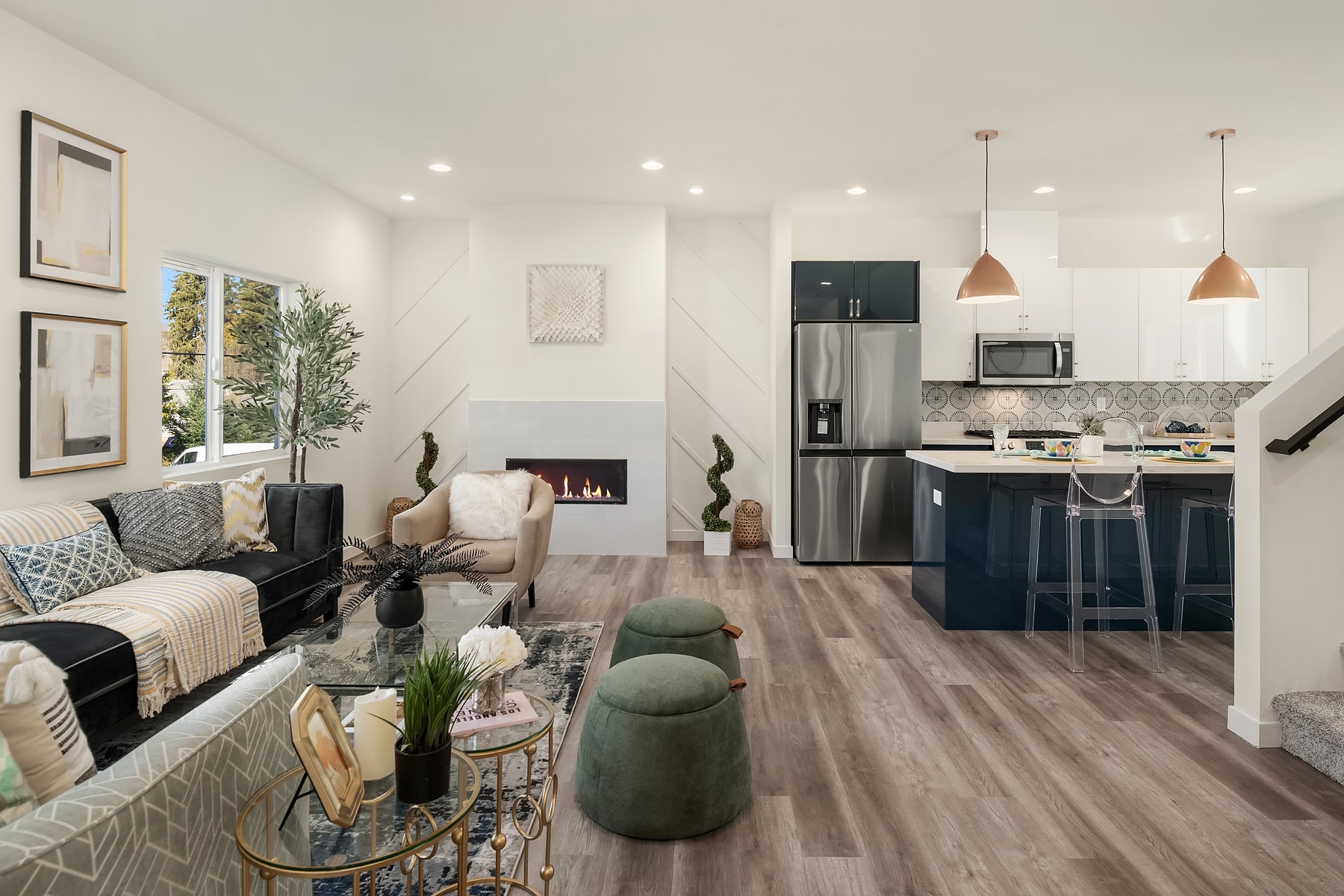An open-concept living room and kitchen with a modern fireplace, stylish seating, and a blue kitchen island, showcasing a contemporary interior layout.