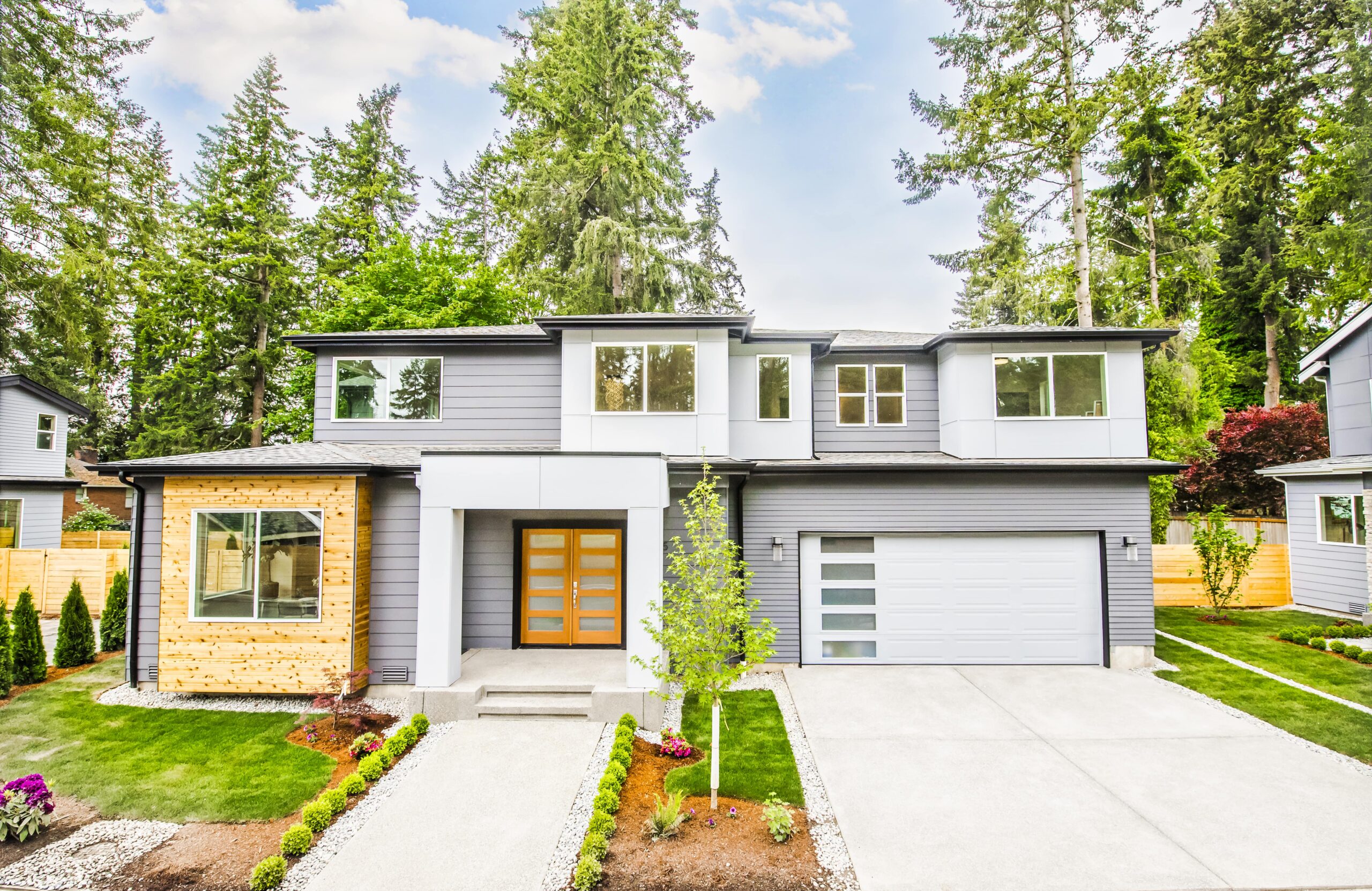A newly built, stylish suburban home with a gray and wood exterior and a two-car garage, representing a contemporary design by TP Home Builds