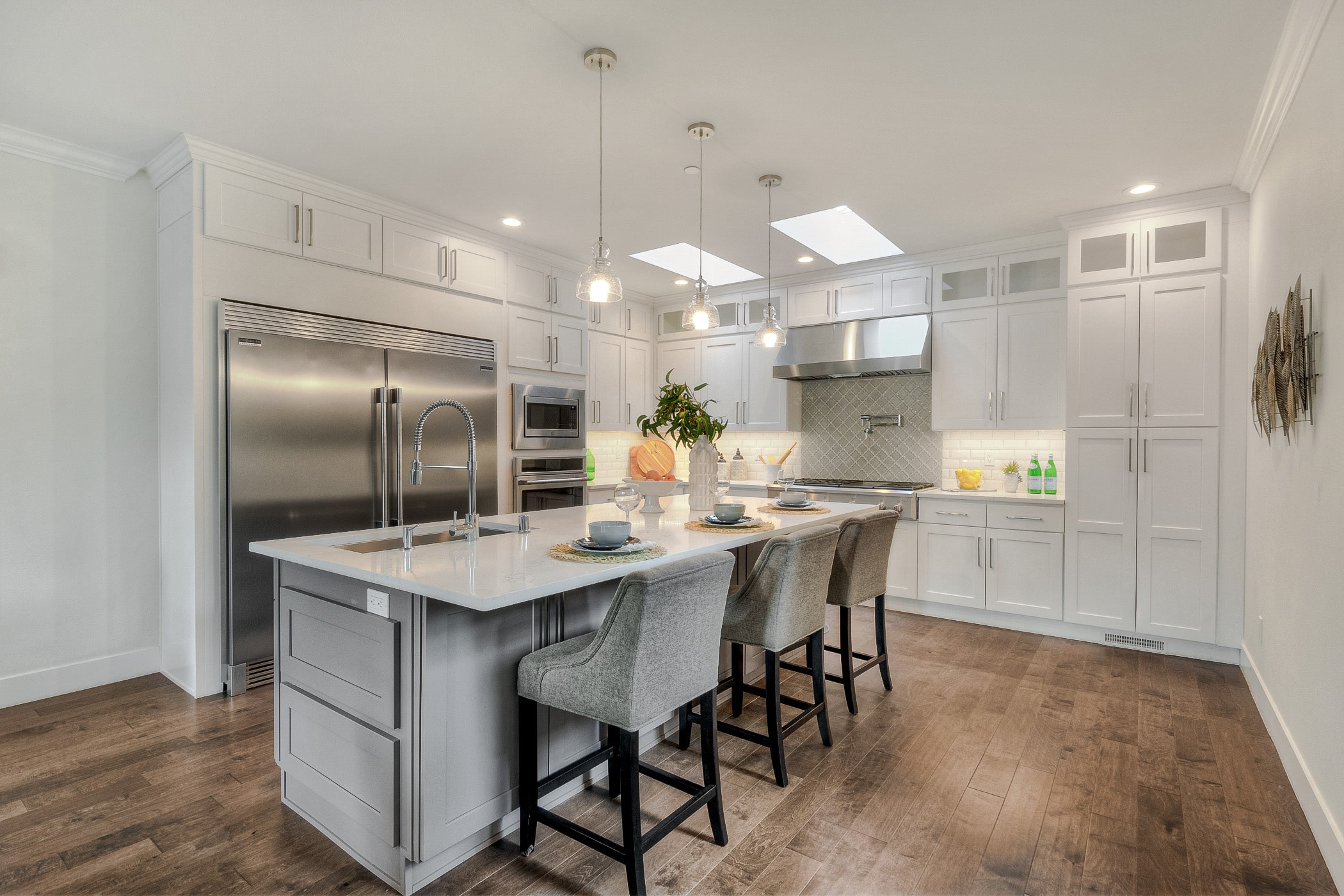 A bright, open kitchen featuring a large central island, white shaker cabinets, and stainless steel appliances, representing a premium interior layout from TP Home Builds. 