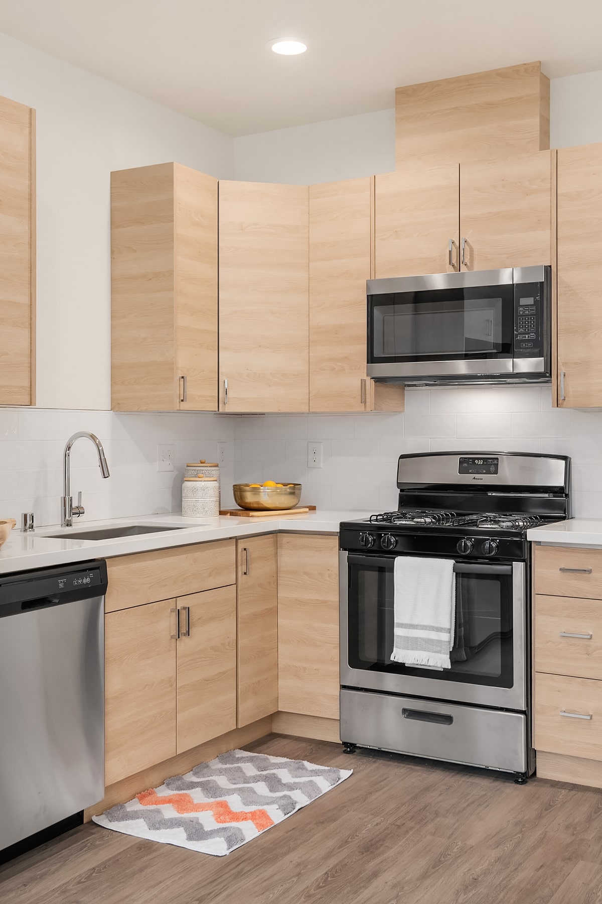A compact, stylish kitchen with light wood-tone cabinets and a white subway tile backsplash, representing an efficient and modern kitchen design by TP Home Builds.