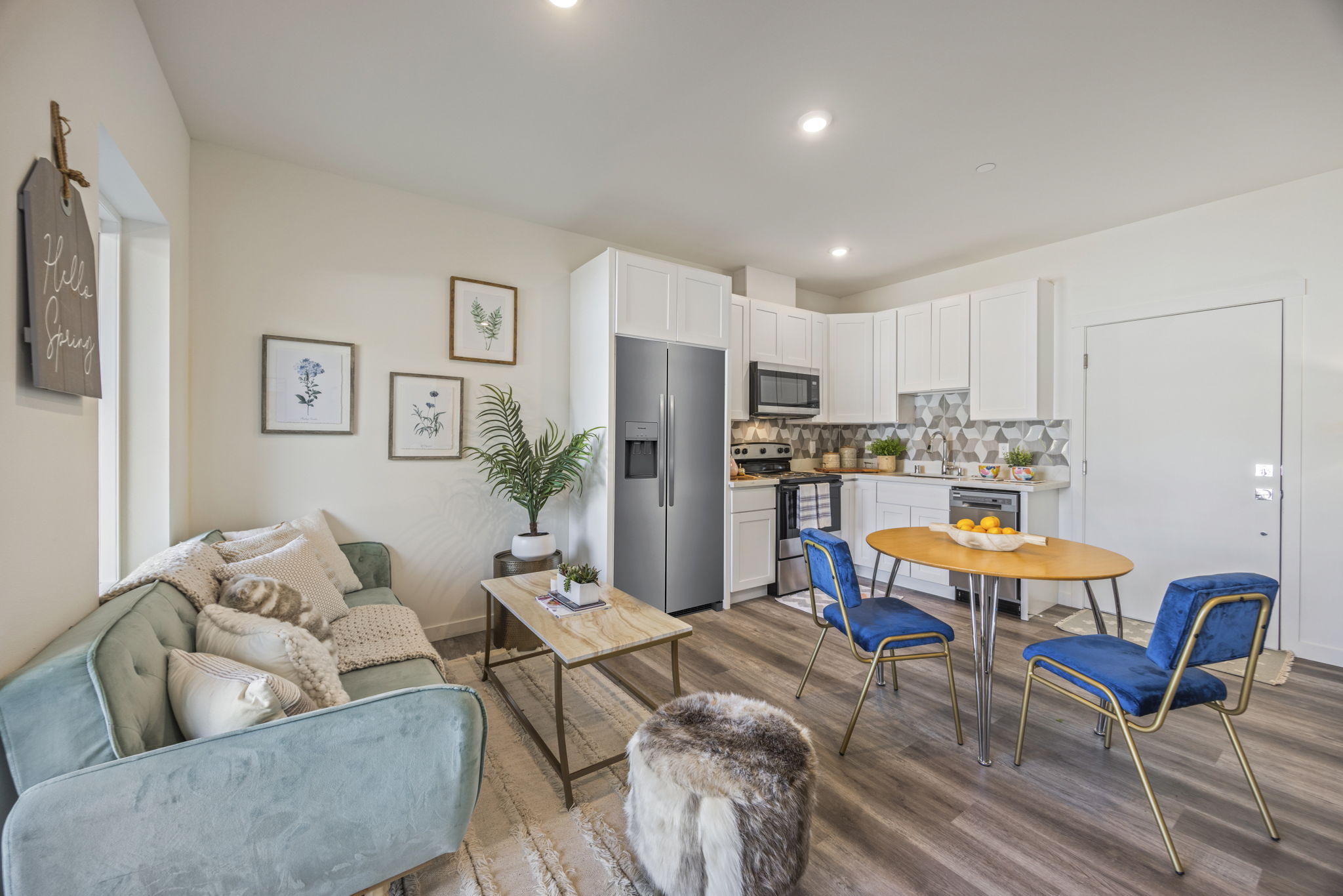 A view of an open-concept apartment unit, showing the living area with a plush couch and a full kitchen, completed by TP Home with high-quality surfaces.