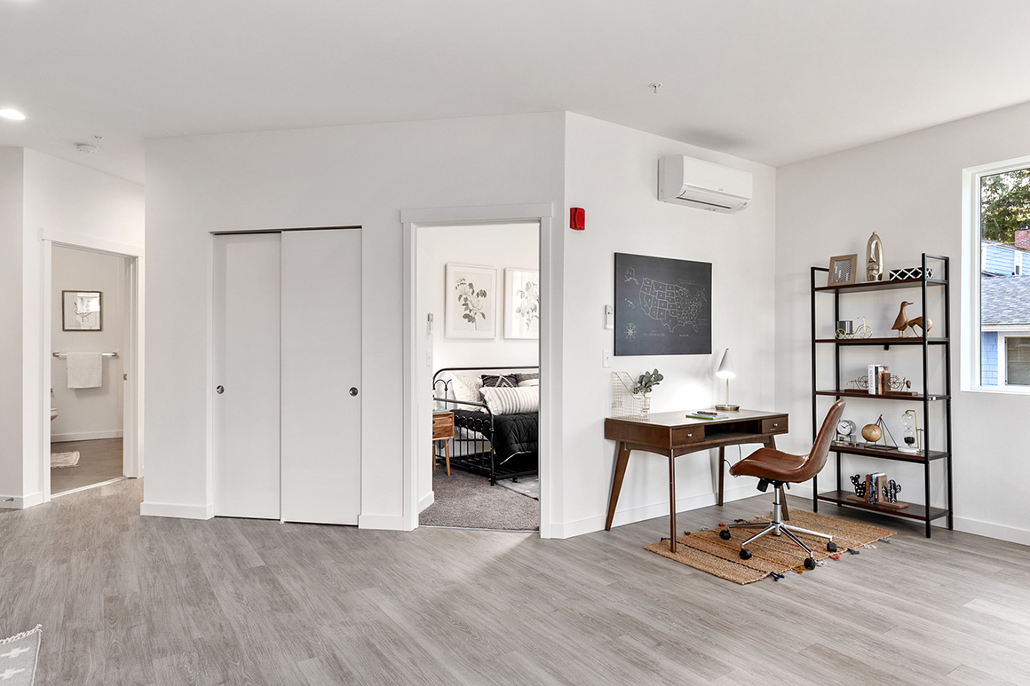 An apartment interior showing a functional living space with a home office area, demonstrating the versatile floor plan of a TP Home unit.