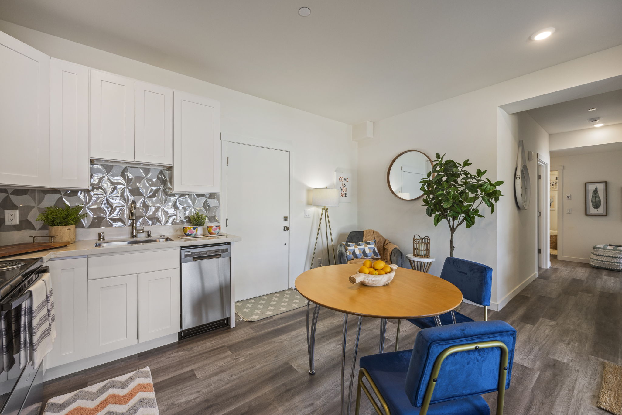 A vibrant apartment kitchen with white cabinets, a patterned backsplash, and a cozy dining area, illustrating a stylish interior design.
