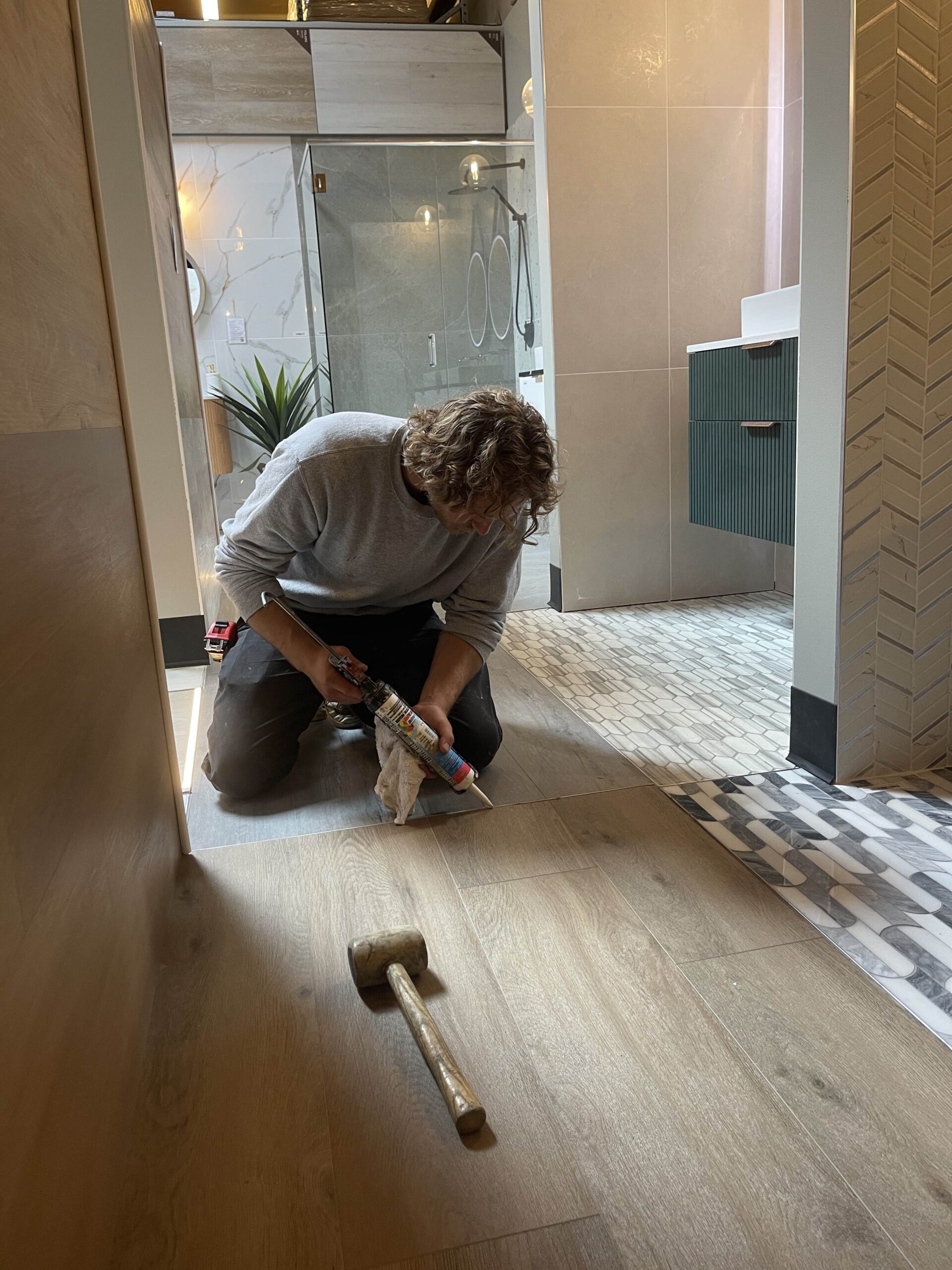 A construction worker applies sealant to a floor, showcasing the final installation stage of interior finishes in the TP Home-built showroom.