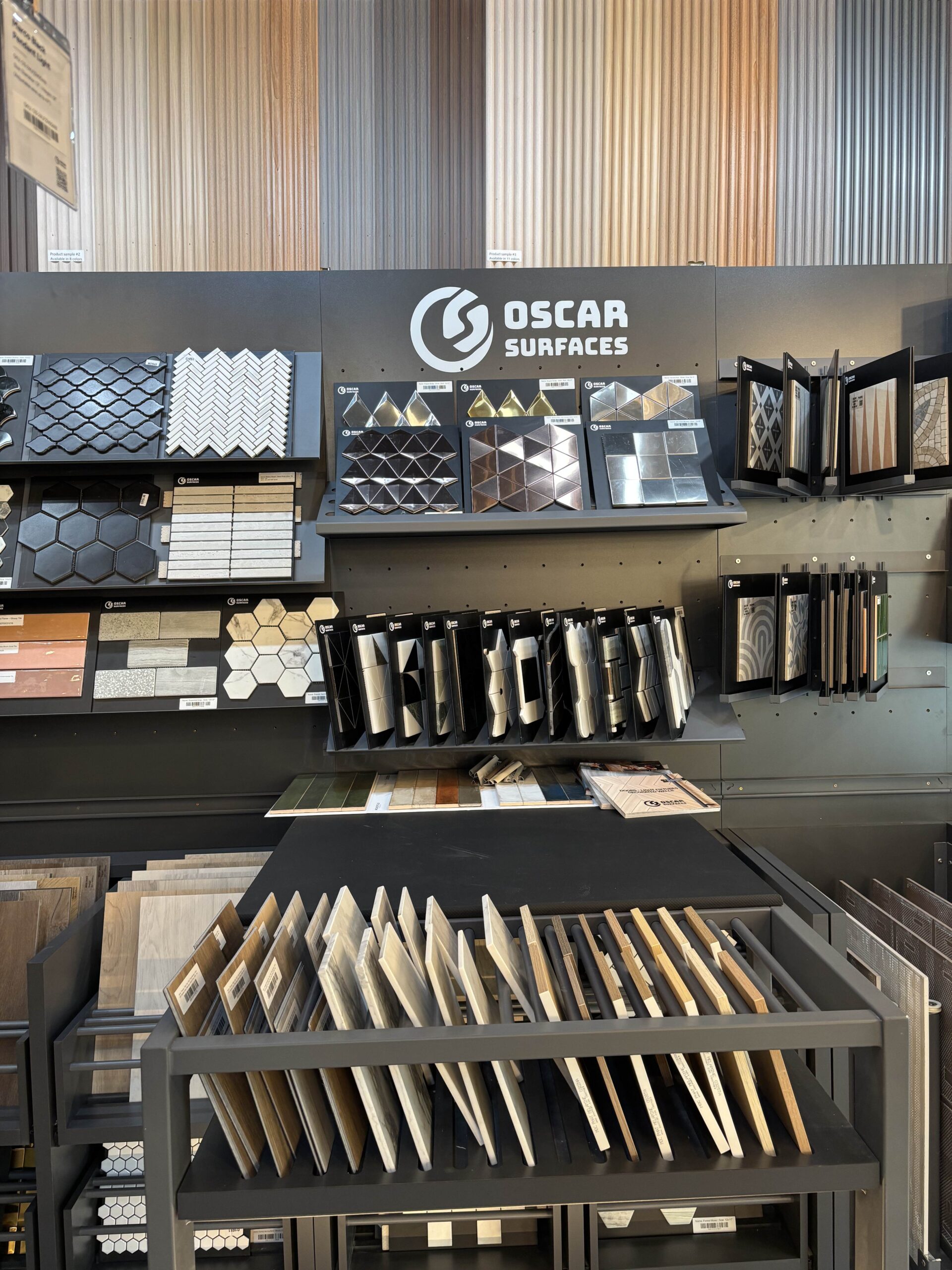 An organized showroom display wall featuring a wide variety of tile and mosaic samples, highlighting the extensive product range available from Oscar Surfaces.
