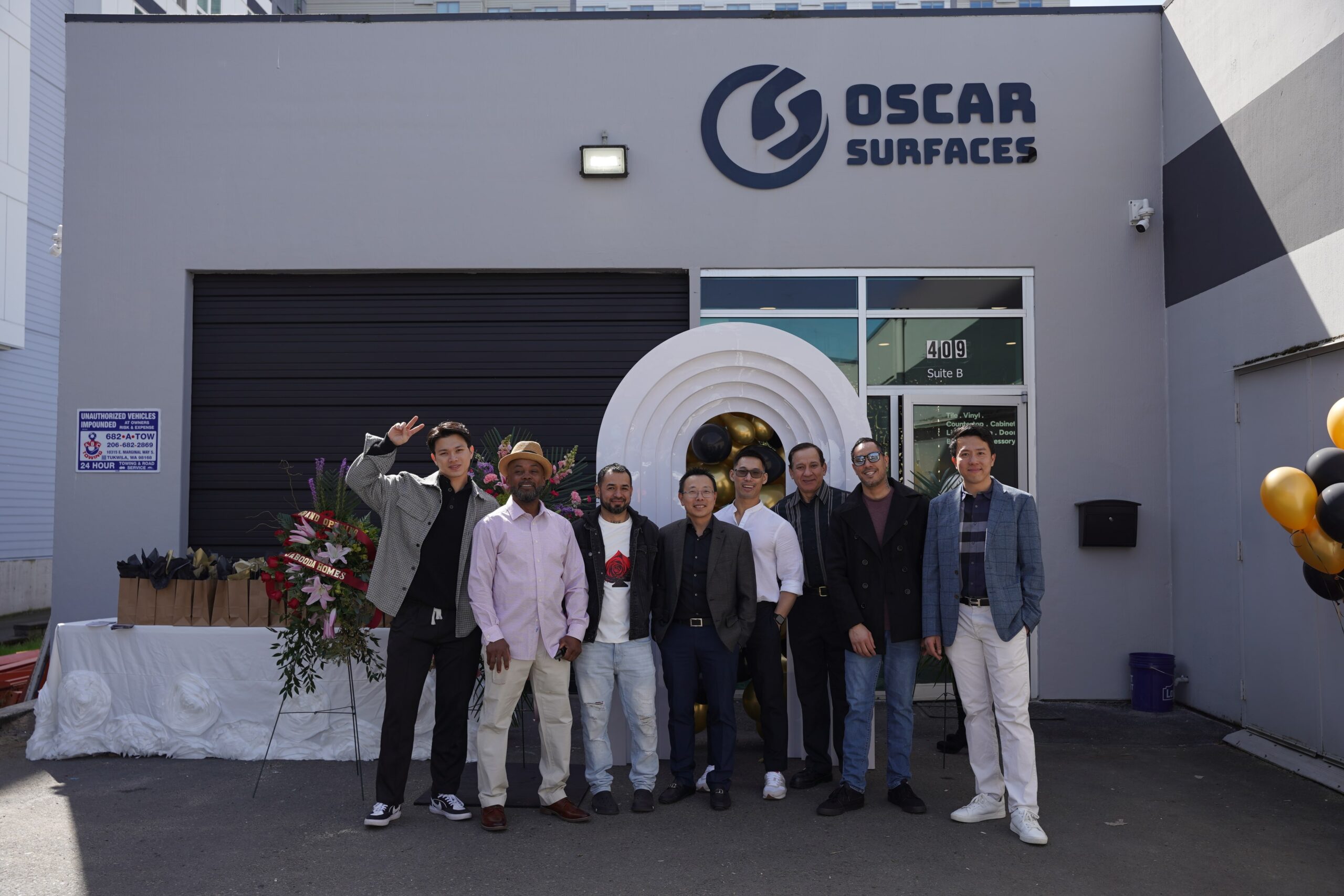 A group of business partners and staff pose for a photo in front of the new Oscar Surfaces showroom, celebrating the grand opening and successful collaboration.