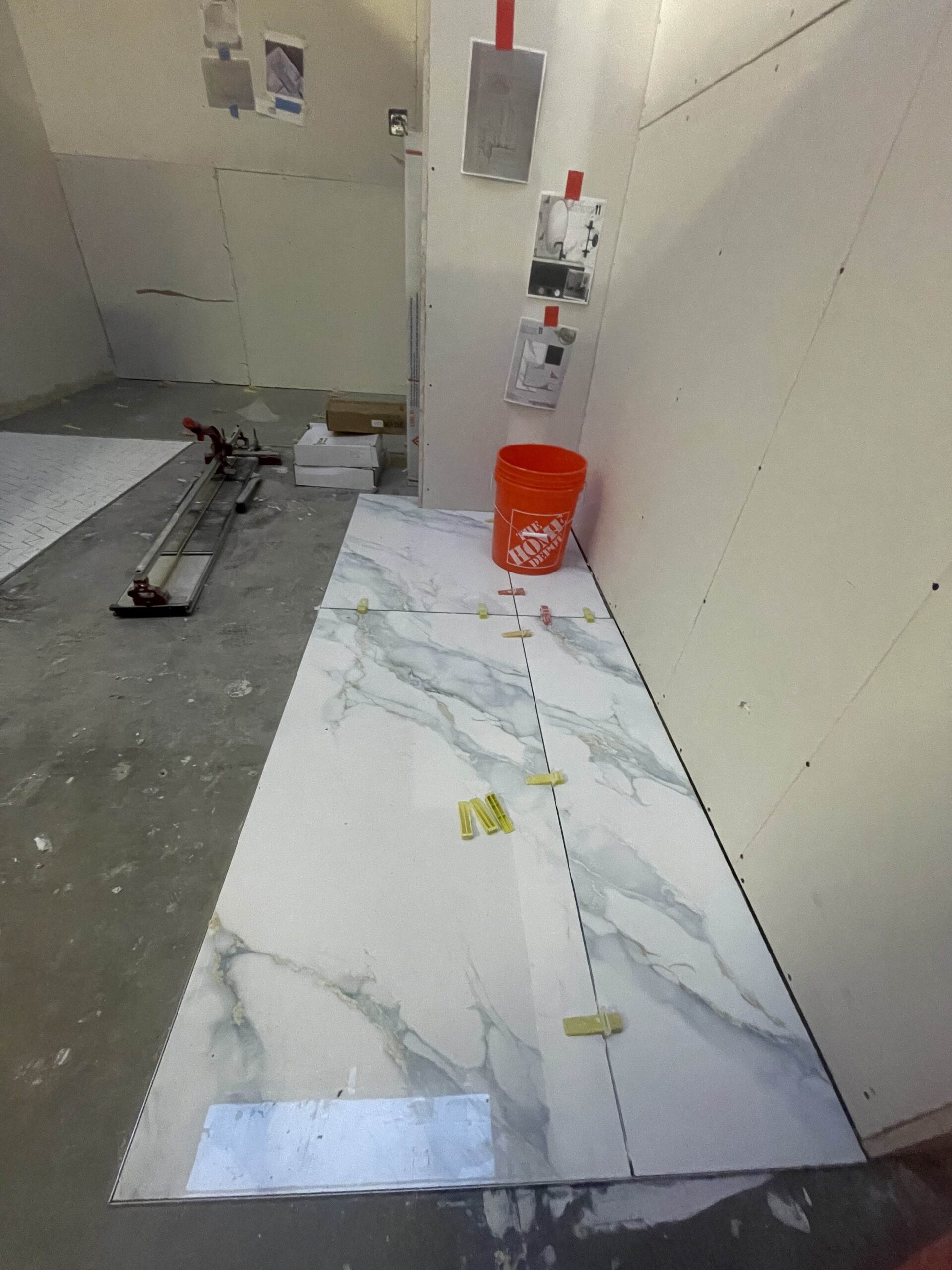 An in-progress shot of the showroom floor with large marble-patterned tiles being installed, showing the construction process of the Tukwilla build.