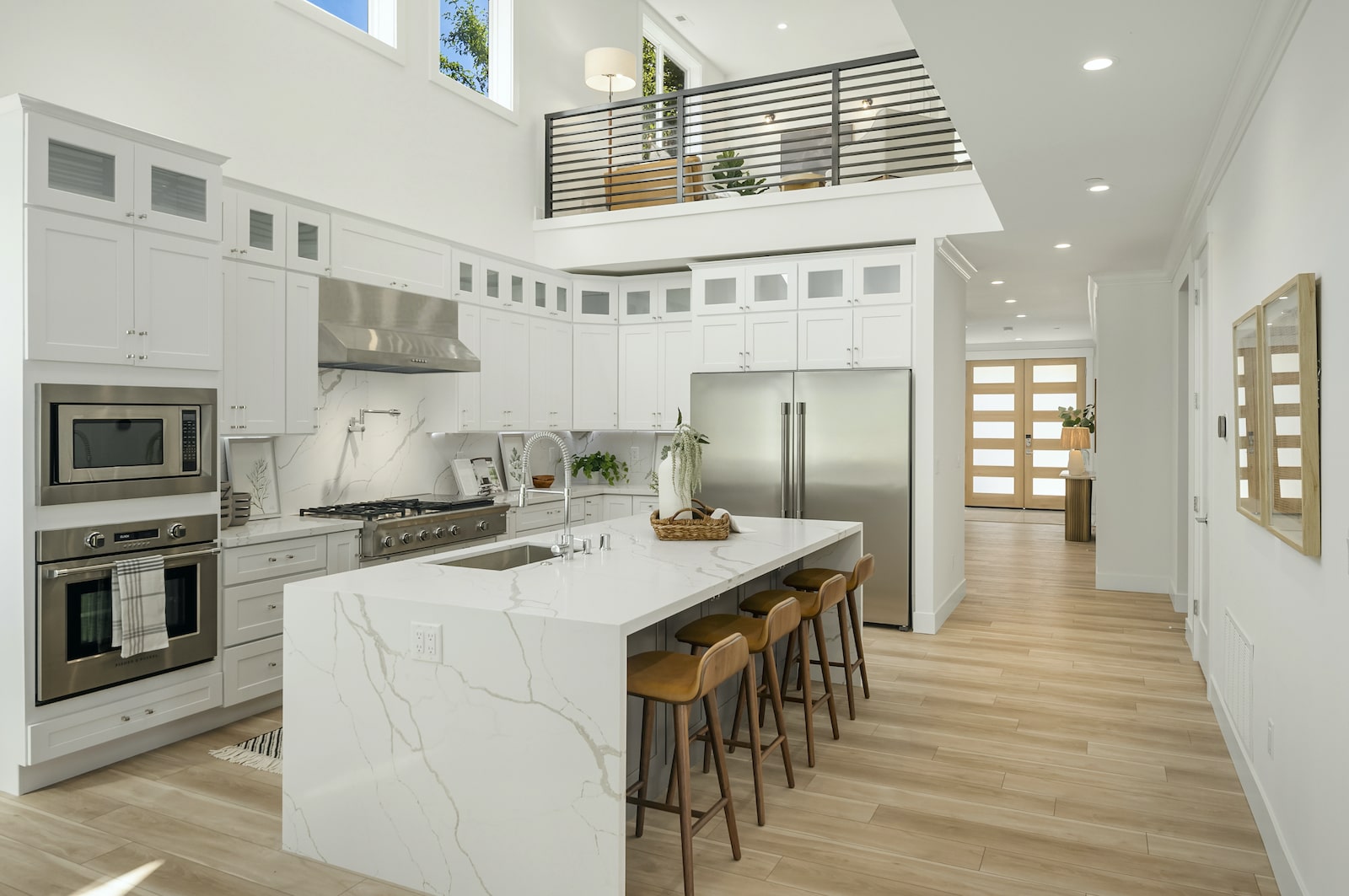 A spacious, modern kitchen with a large marble island, white cabinetry, and an open lofted area, showcasing the high-end design in an ADHG development.
