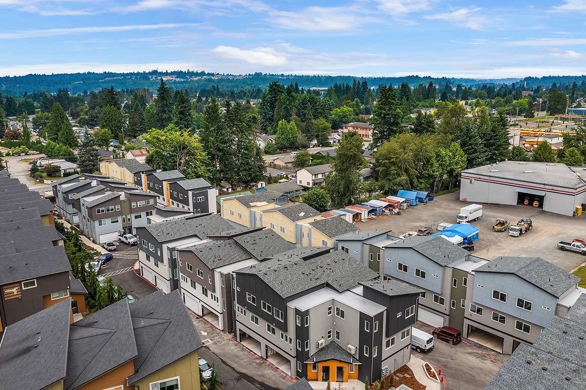 An aerial view of a large residential community featuring a variety of modern townhome designs, illustrating the scale of a TP Home and ADHG development.