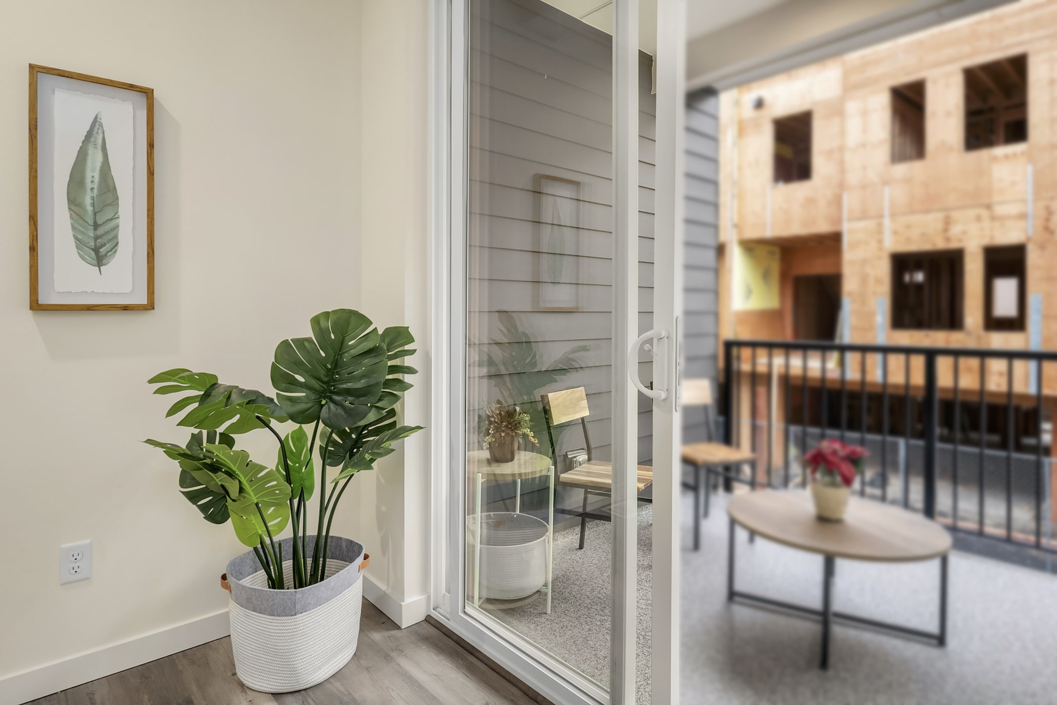 A view from inside a home looking out to a small balcony with a seating area, highlighting the seamless indoor-outdoor living spaces.