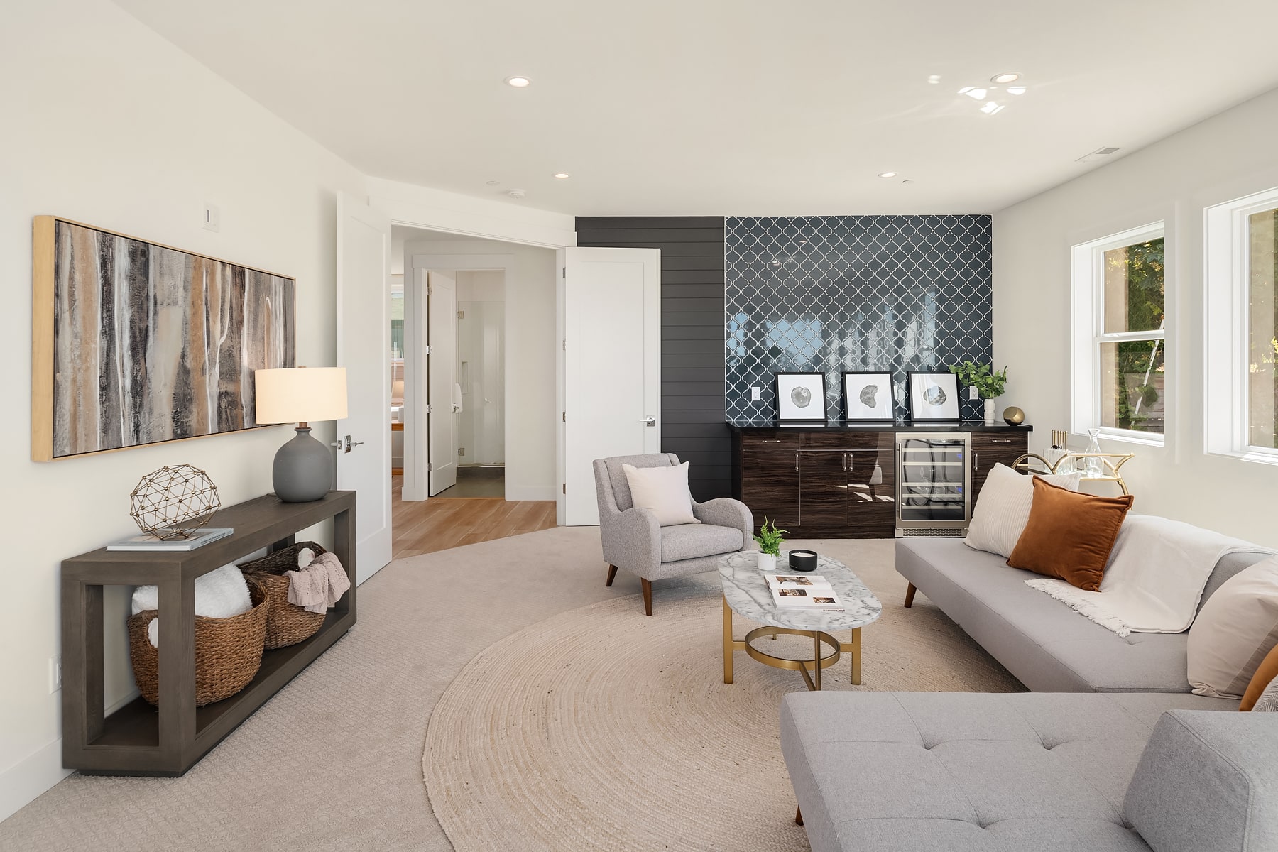 A stylish living room with a built-in wet bar and wine refrigerator, showcasing a premium entertaining space in an ADHG development.