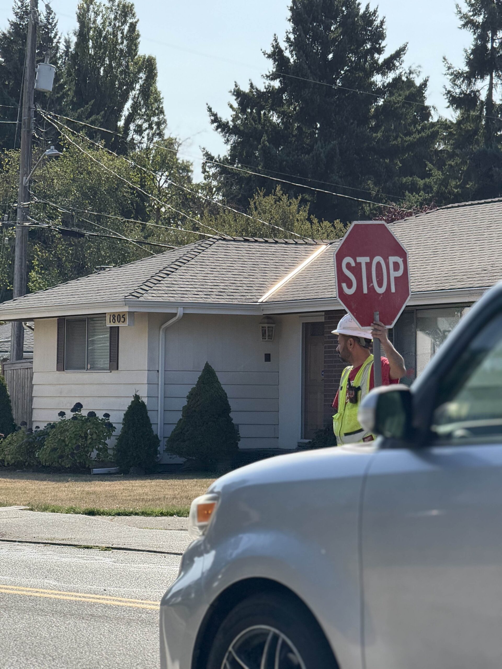 A construction worker holds a stop sign in front of a house, emphasizing the focus on safety and careful management during development.