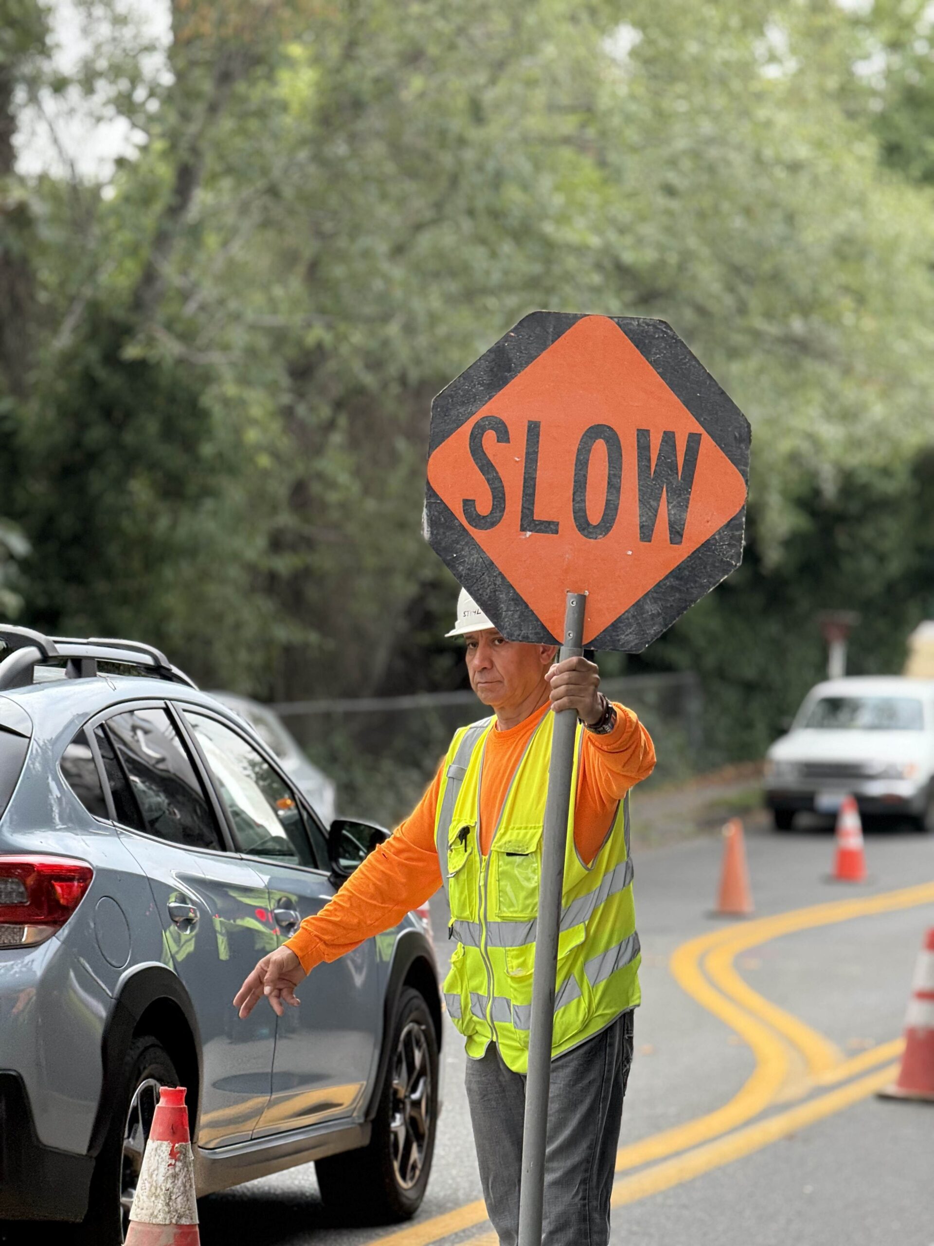 A construction worker holds a 'SLOW' sign, emphasizing the focus on safety and traffic management at TP Home's construction sites.