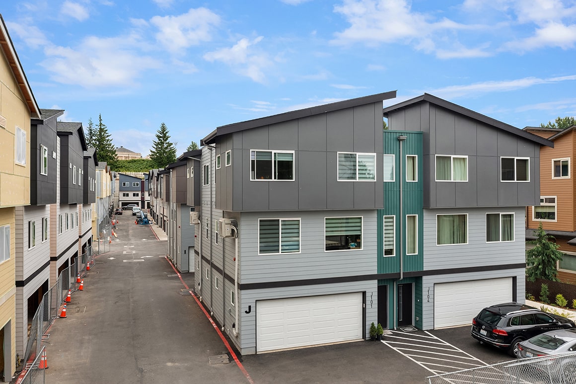 A block of modern townhomes with mixed-material siding and large windows, showcasing a vibrant residential community.