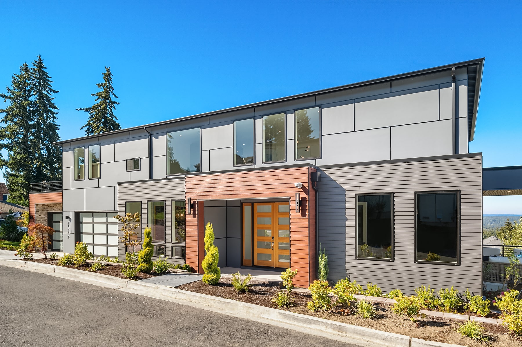 A newly built contemporary home with a clean gray facade and warm wood accents, representing a completed residential project by TP Home.