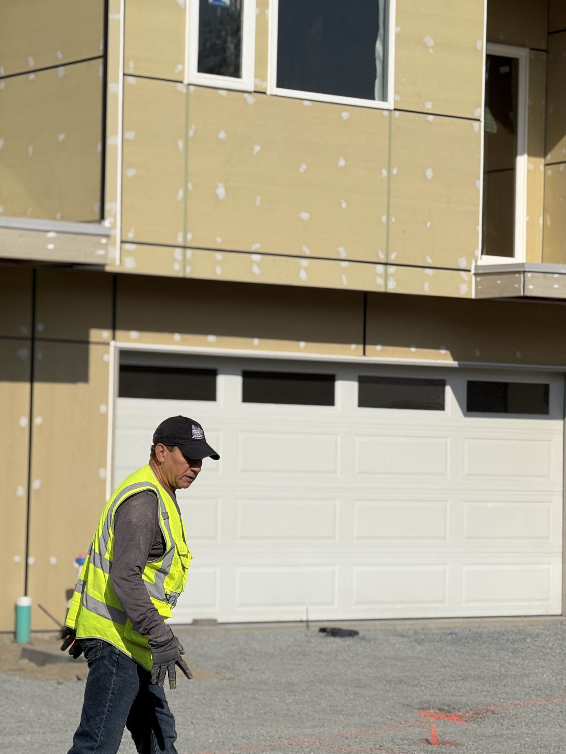 A construction worker walks on-site in a high-visibility vest, representing the skilled workforce of TP Home's excavation partners in Washington.