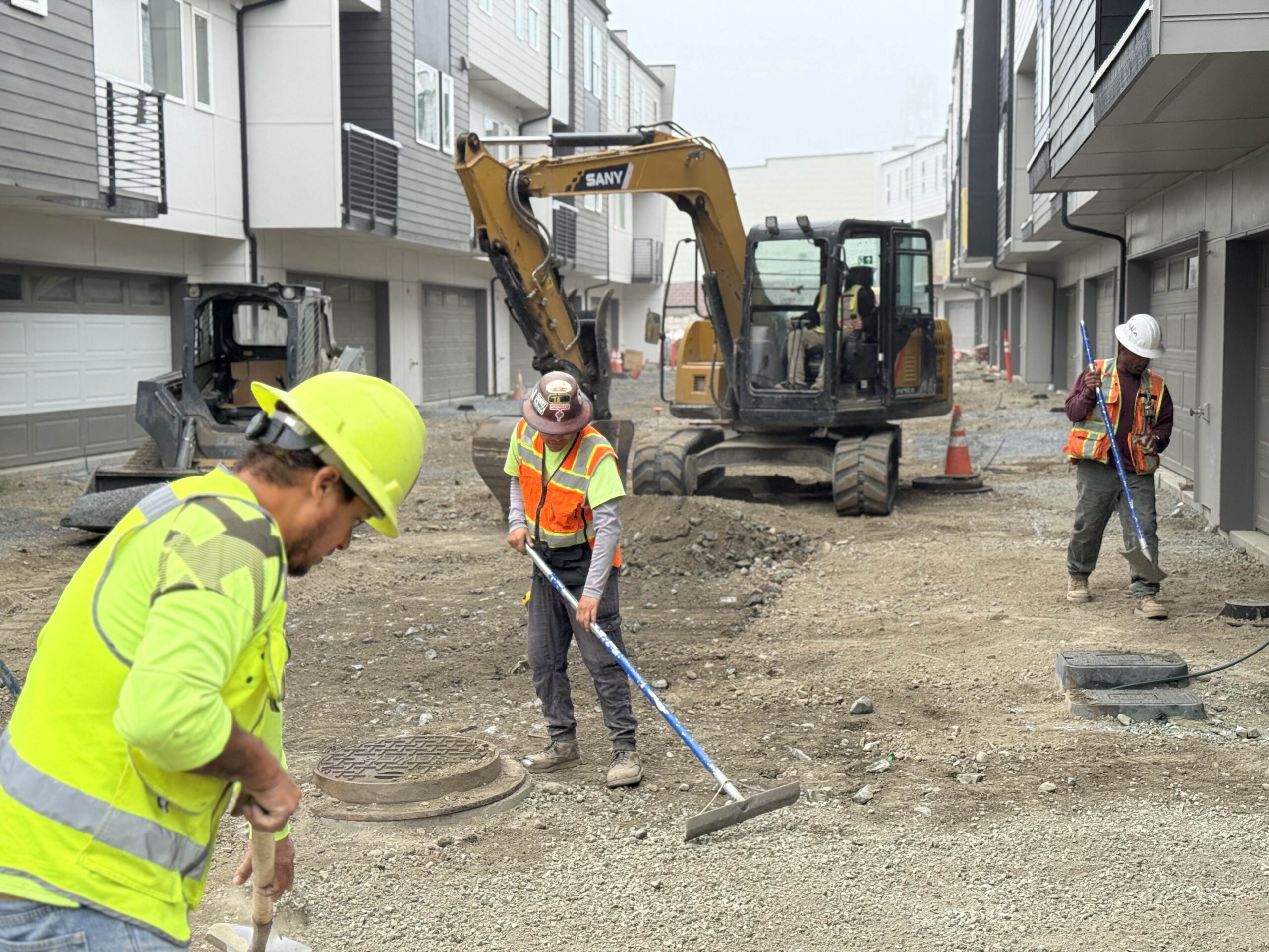 Construction workers and heavy machinery on-site, illustrating the teamwork and large-scale operations required for new housing projects.